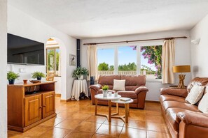 A living room with a TV, two sofas, a coffee table, and a cabinet.