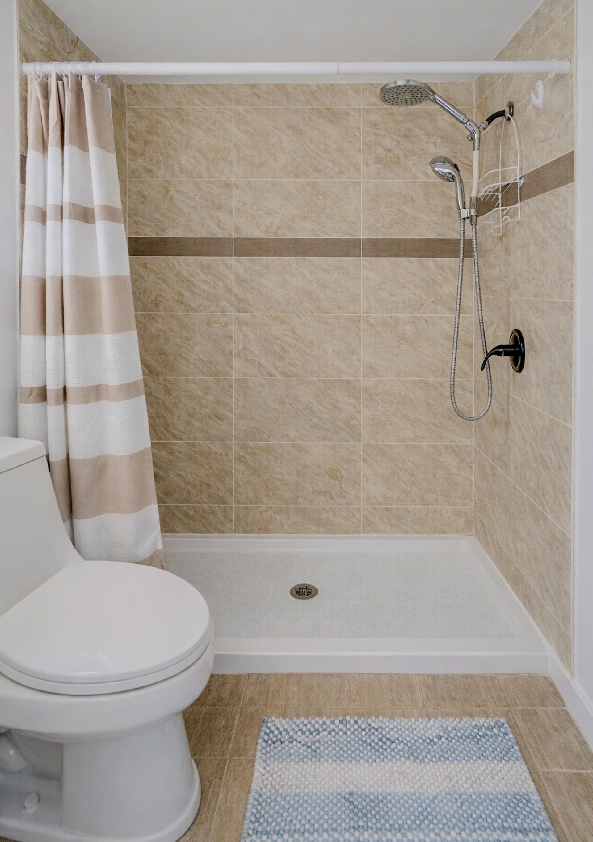 A bathroom with a shower, toilet, and a striped curtain.