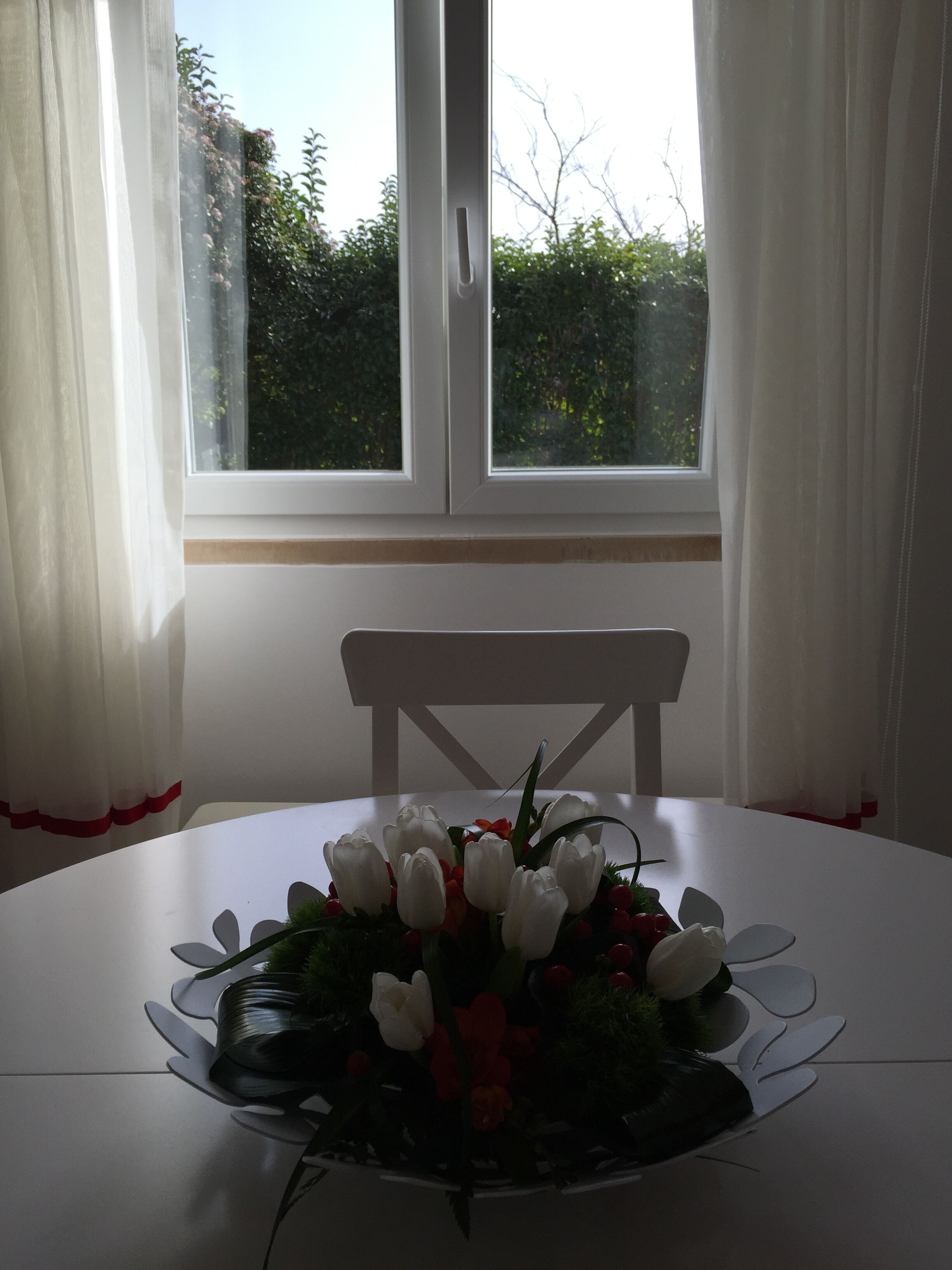 A round table with a white tablecloth, a white chair, and a floral centerpiece.
