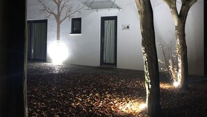 A building with two visible windows and a door, surrounded by trees and a leaf-covered ground. - Horta dos Cedros  (Tomar)