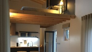 A modern living room with a sofa, a dining area, and a kitchen visible through an open door. - Horta dos Cedros  (Tomar)
