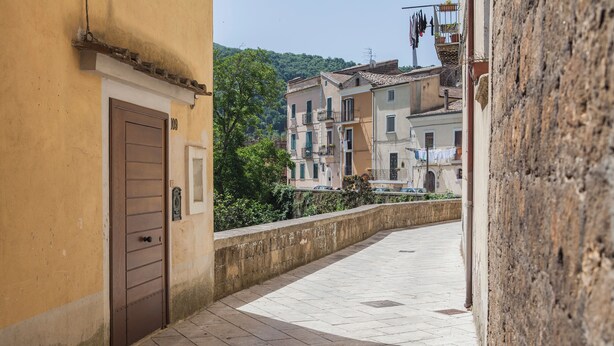 Un stretto vicolo con un muro di pietra da un lato e l'ingresso di un edificio dall'altro.