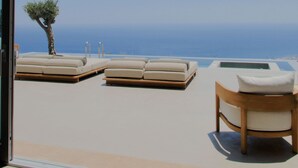 Een balkon met lounge stoelen en een tafel, met uitzicht op een heldere blauwe lucht en zee.