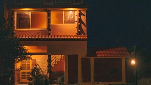 A two-story building with a red-tiled roof, a staircase leading to the entrance, and a small porch area. - MVT Resort & Restaurant (Rishikesh)