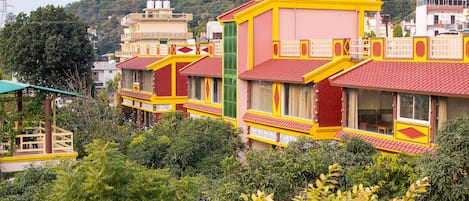 A row of colorful buildings with red and yellow facades, surrounded by dense greenery.