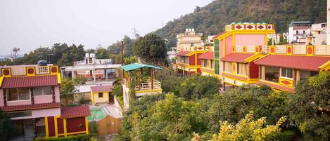 A residential area with colorful houses, a green-roofed structure, and a hillside in the background.