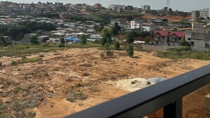 A view from a balcony overlooking a residential area with various buildings, some under construction, and a clear sky with clouds. - Prestige Family Suite, 2 Spacious Bedrooms with Balcony Exceptional setting (Abidjan)