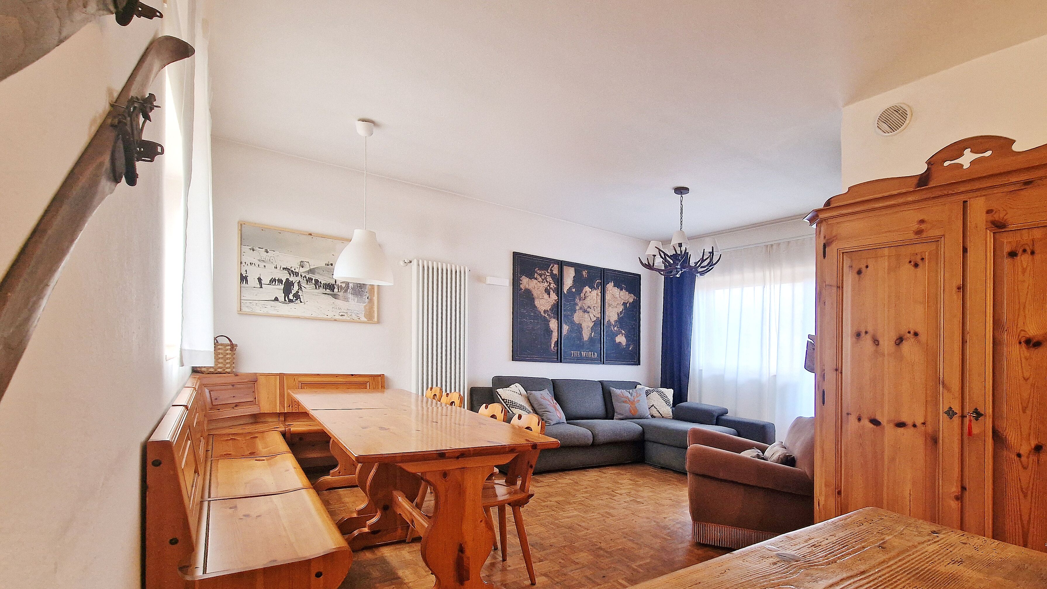 A cozy living room with a wooden dining table, a sofa, and a large wooden cabinet.