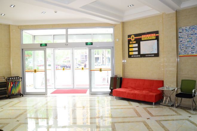 Un hall con un sofá rojo, una mesa de vidrio y un felpudo rojo en la entrada.
