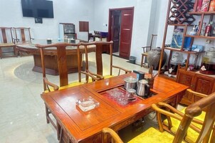 Un comedor con una mesa y sillas de madera, un televisor montado en la pared y una estantería con diversos objetos.
