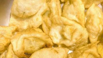 Primer plano de un alimento, probablemente una especie de pastel frito o albóndiga, con una capa exterior dorada.