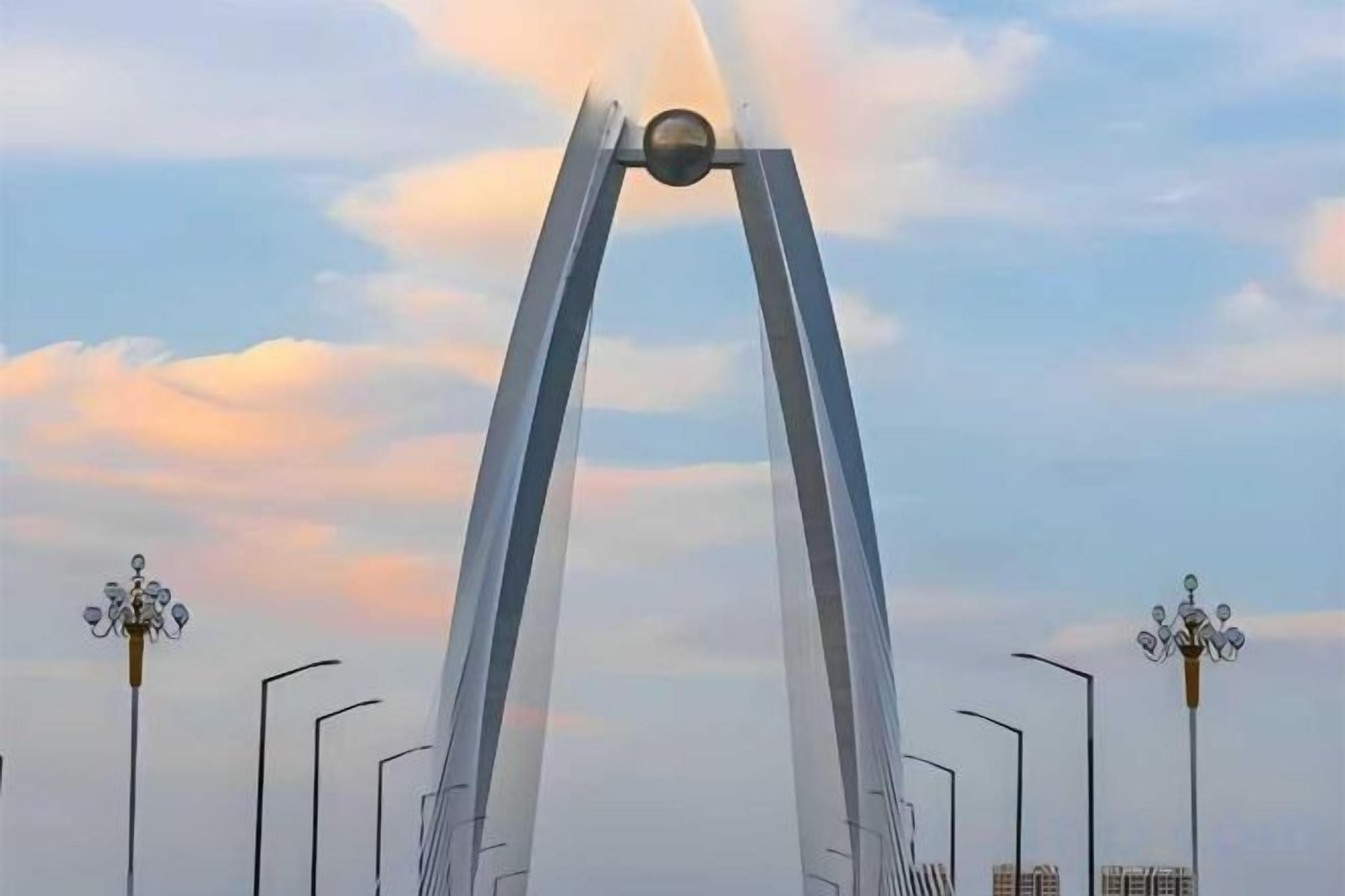A bridge with two tall arches and street lamps on either side.