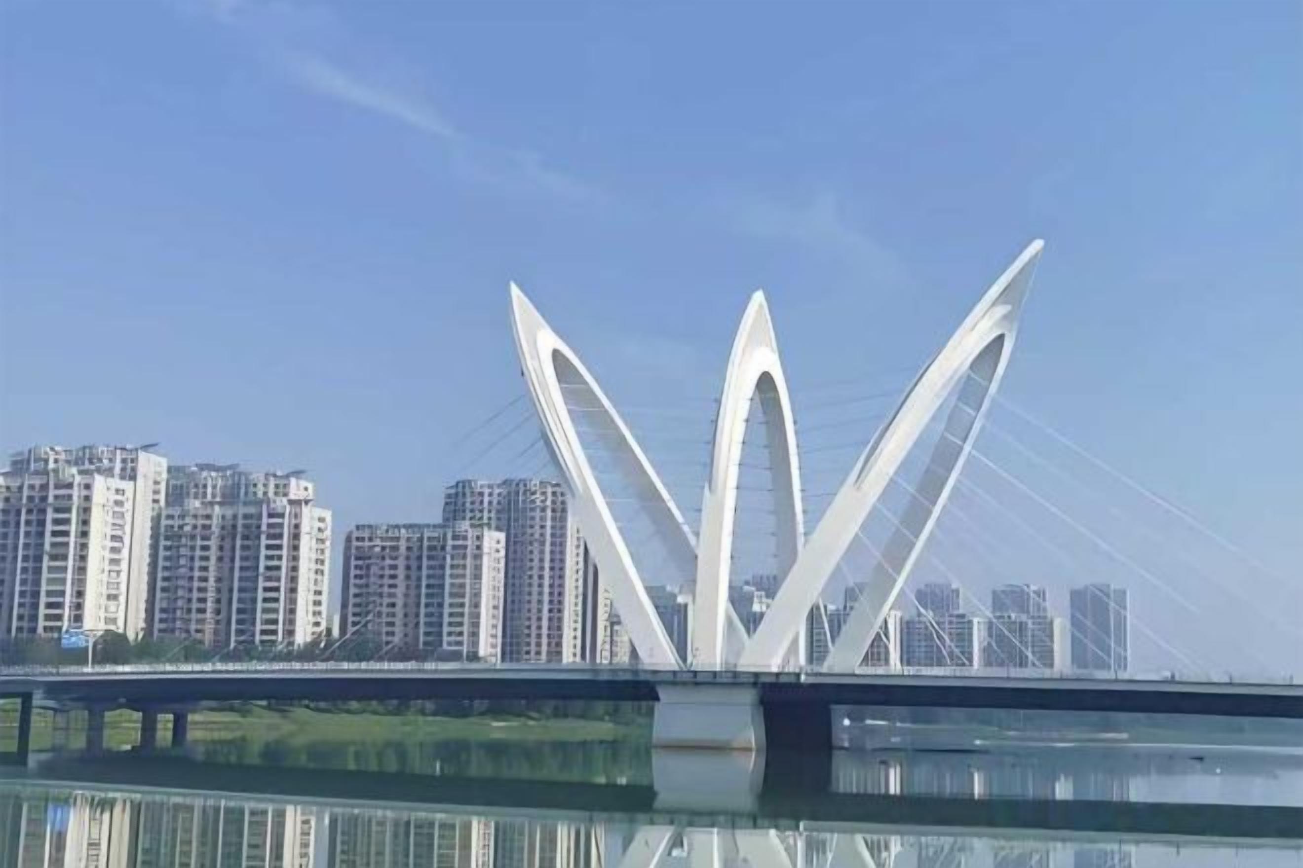 A modern bridge with a unique design, featuring multiple arches and cables, spanning over a body of water with high-rise buildings in the background.