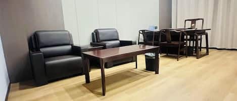 Una sala de conferencias con una mesa de madera, cuatro sillas y un basurero.