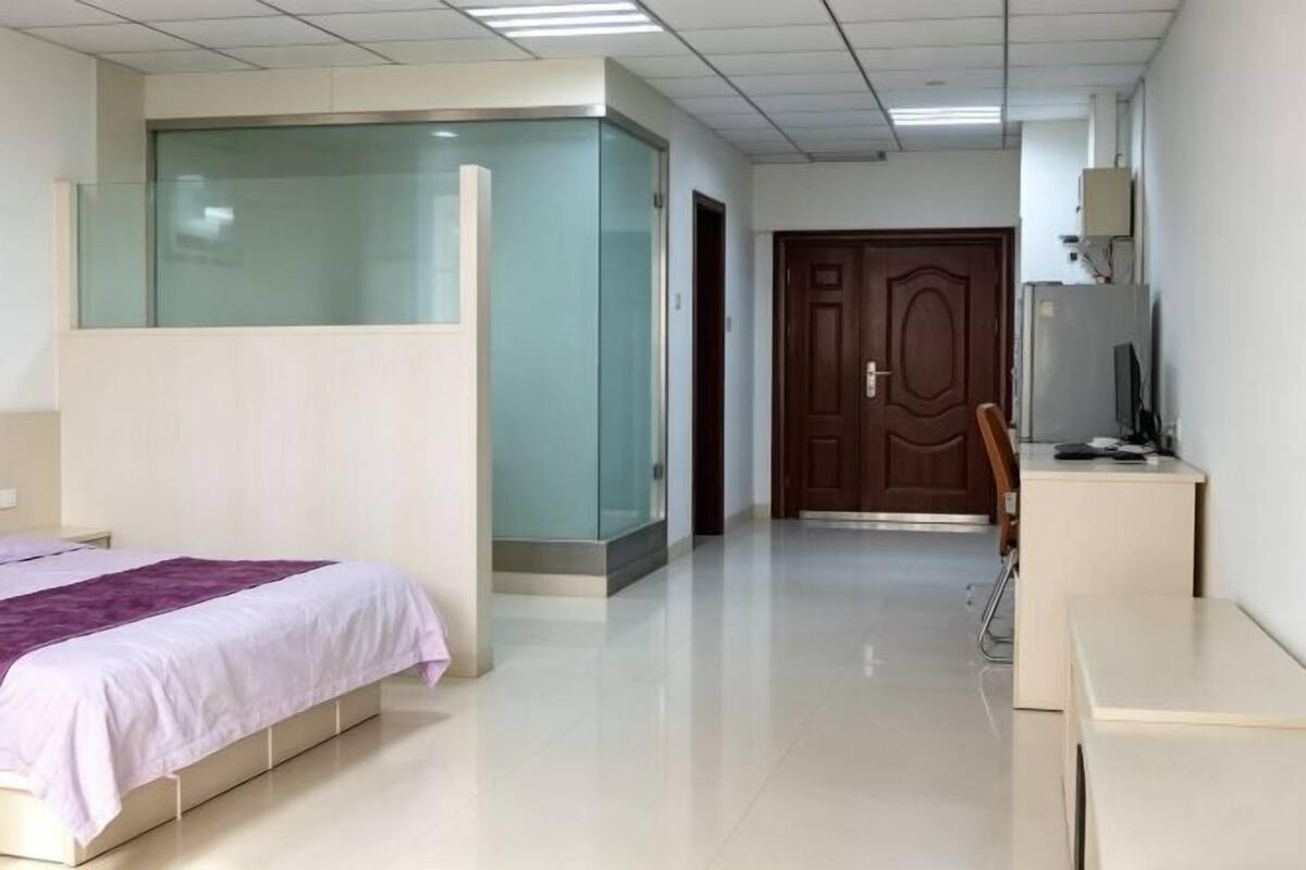 A hotel room with a bed, a desk, a chair, a wardrobe, and a door.