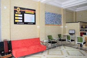 A hotel lobby with a reception desk, a red sofa, and a bulletin board with information.