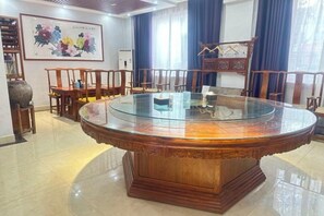 A round wooden table with a glass top surrounded by wooden chairs, a decorative vase, and a framed artwork on the wall. - Super 8 Hotel (Zhenhua Shopping Center, Liaocheng Development Zone) (Liaocheng)