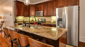 A kitchen with wooden cabinets, stainless steel appliances, granite countertops, and pendant lighting. - Downtown Lancaster Luxury 4BR - Garage & Parking (Lancaster)