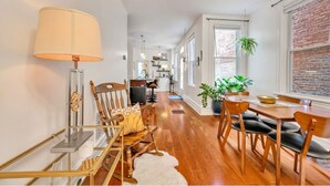 A modern kitchen with a dining area, wooden flooring, and a large window with a plant. - Downtown Lancaster Luxury 4BR - Garage & Parking (Lancaster)