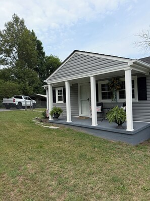 A residential house with a covered porch, a driveway, and a lawn.