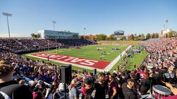 A stadium with a football field, bleachers, and a scoreboard.