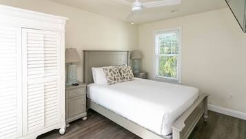 A bedroom with a bed, nightstands, a wardrobe, a ceiling fan, and a window with blinds.