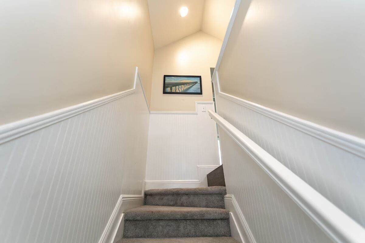 Eine Treppe mit weißer Wandverkleidung und einem Bild an der Wand.