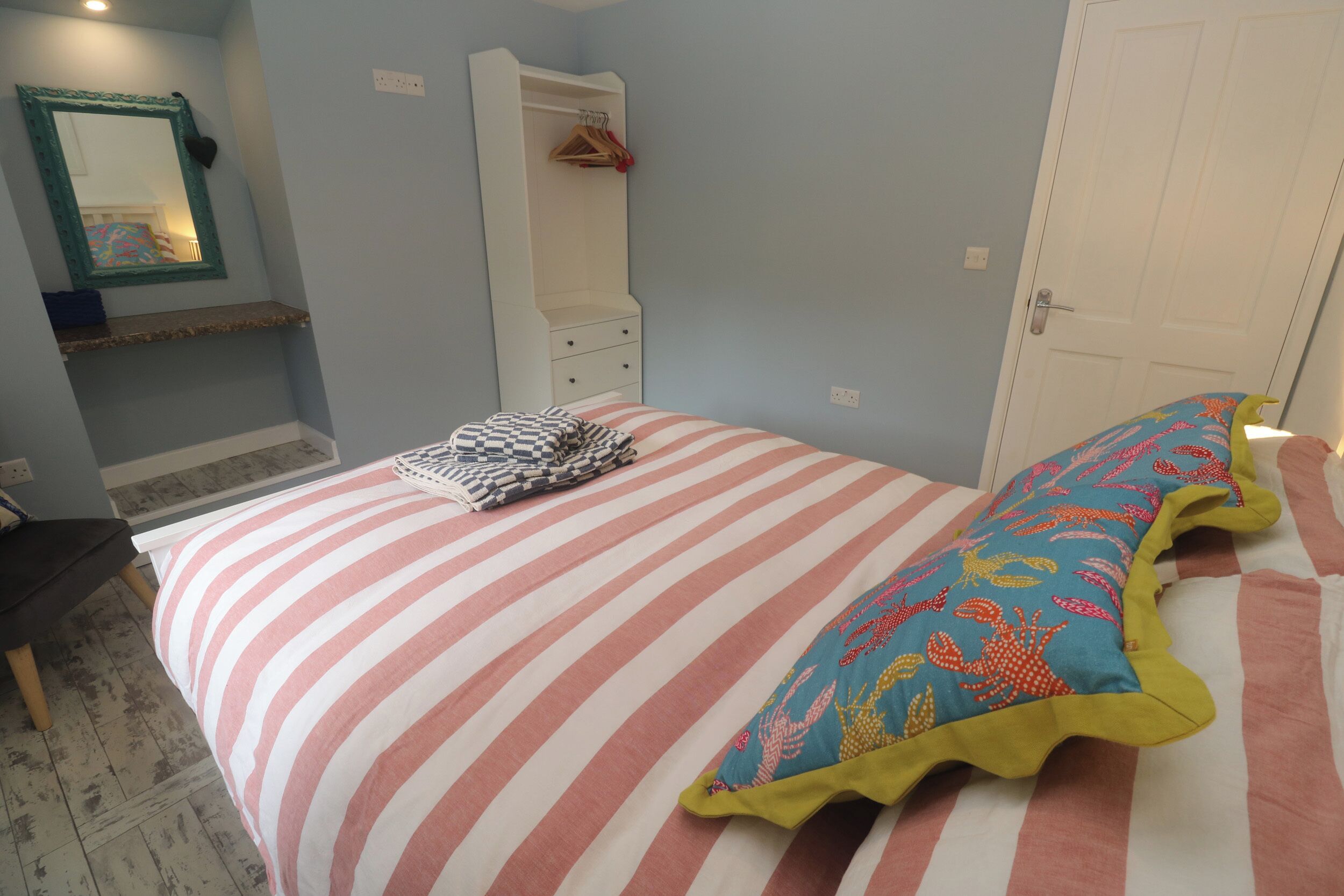 Ein Schlafzimmer mit Bett, Kommode, Spiegel und Tür.