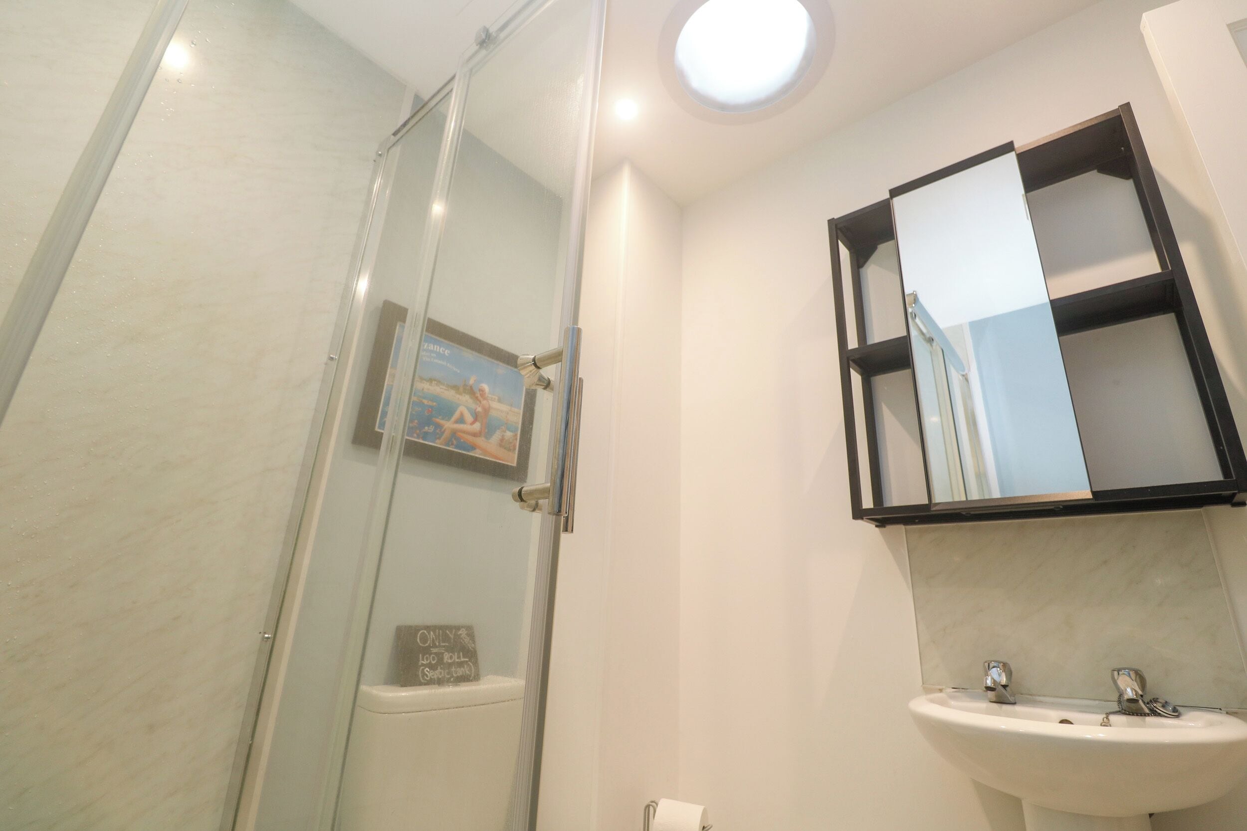 Un baño con cabina de ducha de vidrio, un lavabo y un espejo.