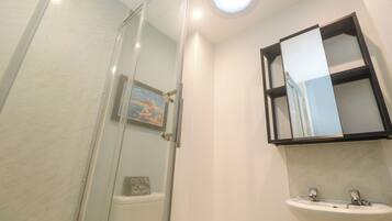 Un baño con cabina de ducha de vidrio, un lavabo y un espejo.