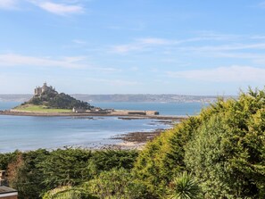 A coastal landscape with a castle on a small island, surrounded by water and greenery. - Sea View Loft (Penzance)