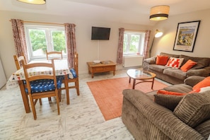 A furnished living room with a sofa, a table, a chair, and a television.