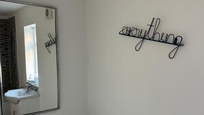 Un baño con inodoro, lavabo, espejo y un cartel en la pared que dice 'todo'.