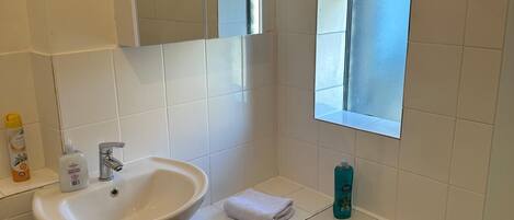 Ein Badezimmer mit Waschbecken, Spiegel, Fenster und Badewanne.