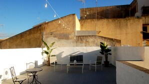 Une terrasse sur le toit avec une table ronde, deux chaises et des plantes en pot.