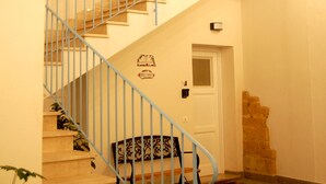 Un escalier avec des rampes bleues, une main courante en bois et un petit banc en bas.