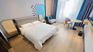 Quarto de hotel moderno com uma cama grande, um sofá pequeno, uma mesa redonda e uma cadeira.