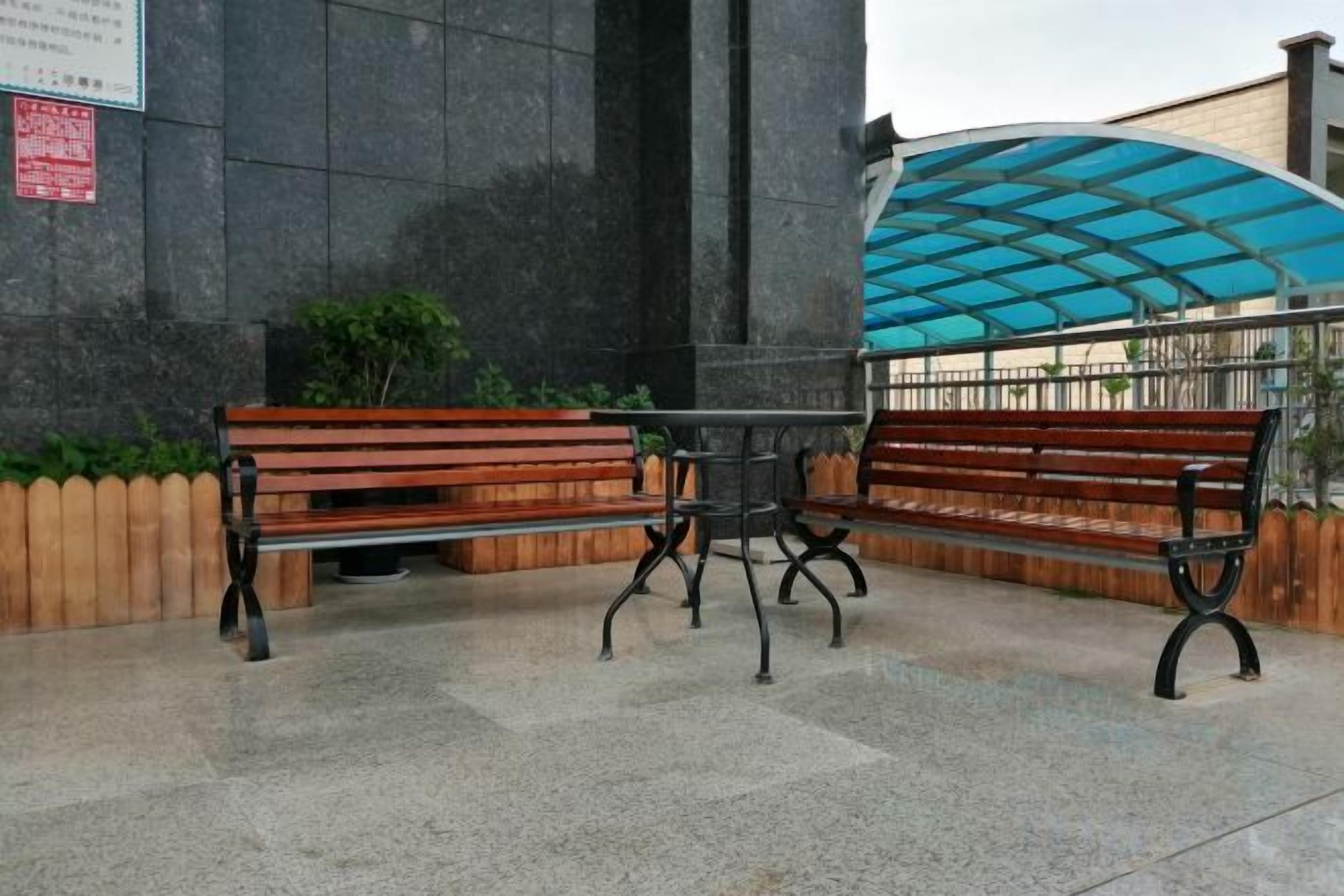Una zona con bancos, un espacio de asientos cubierto y una pared de piedra.