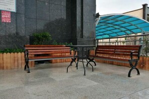 A bench area with a covered seating section and a stone wall. - City Convenience Hotel (Yingcheng Railway Station Shanghe Square) (Yingcheng)