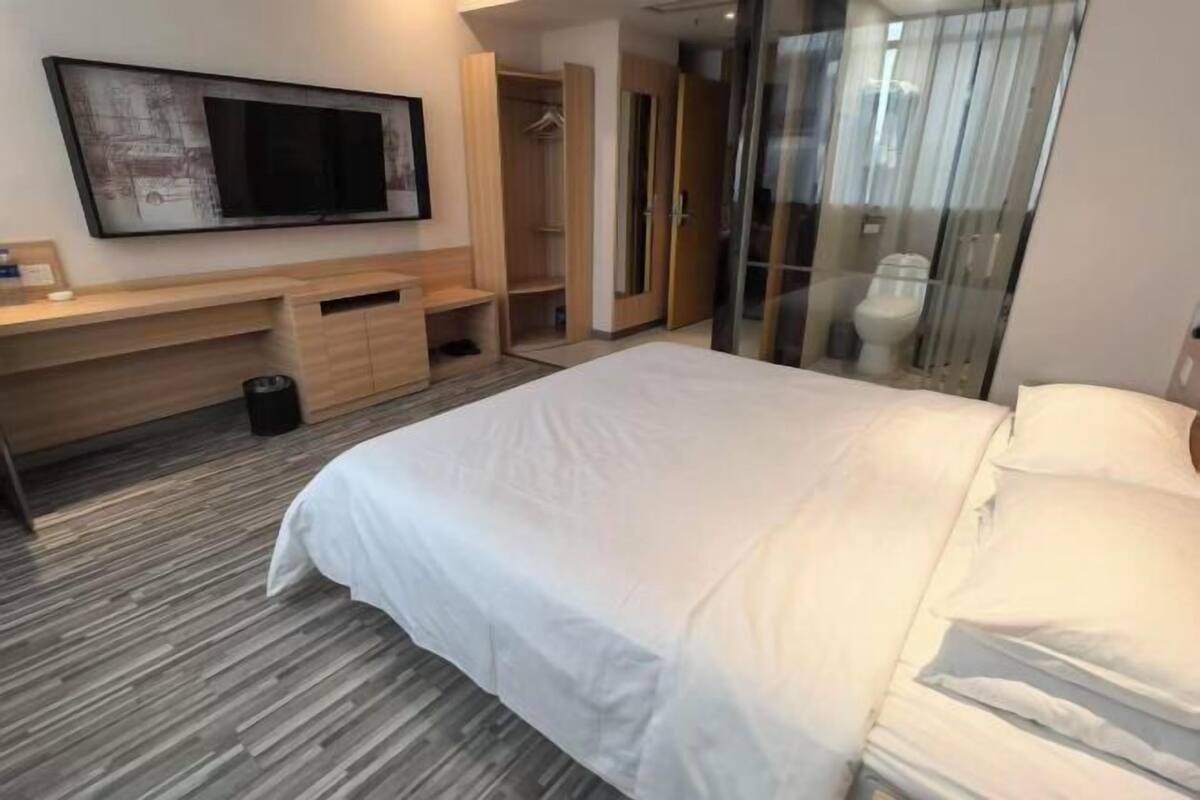 A hotel room with a bed, a desk, a television, and a wardrobe.