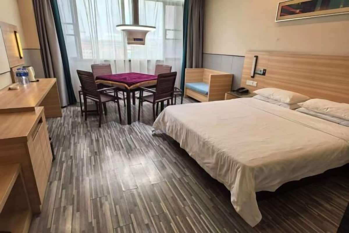 A hotel room with a bed, a desk, a chair, and a table.