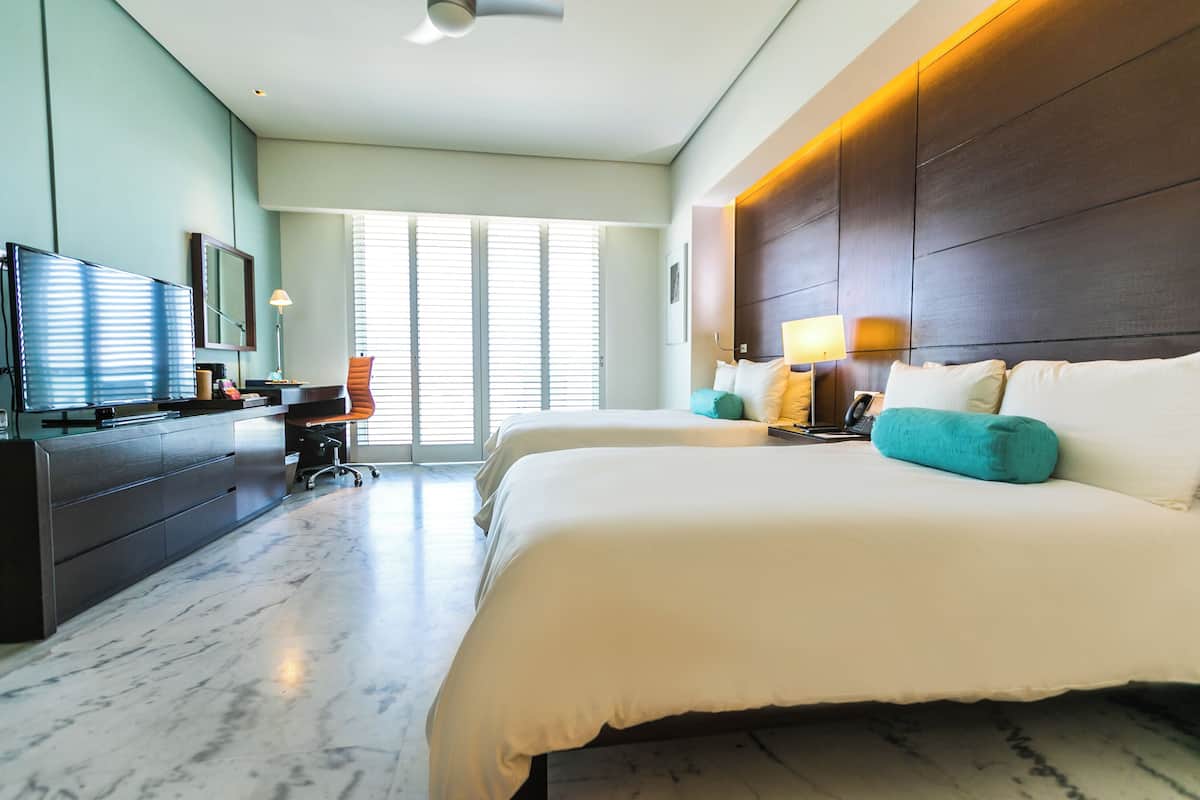 Quarto de hotel moderno com uma cama grande, uma escrivaninha e uma televisão.