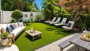 A backyard with a lawn, a white fence, a sofa with cushions, a coffee table, and lounge chairs. - Walk to siesta key (Siesta Key)