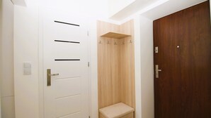 Um corredor com uma porta branca, uma porta de madeira e um pequeno banco de madeira.