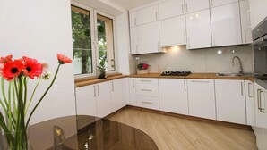 Cozinha moderna com armários brancos, bancada de madeira e fogão a gás.