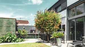 A modern building with large windows, a well-maintained garden, and outdoor seating. - STAY AT THE ZEN LOFT (Bordeaux)