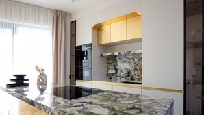 A modern kitchen with a marble countertop, stainless steel appliances, and a gold accent wall. - Villa Noles (Sukošan)