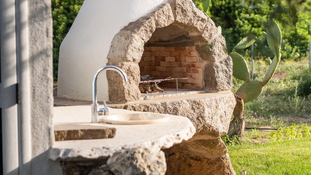 A stone oven with a chimney, a sink, and a stone ledge. - Villa Fior D'acqua - Castelsardo (Castelsardo)