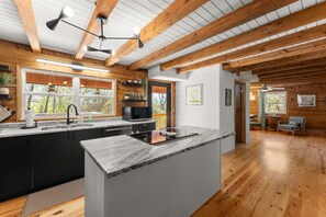 A modern kitchen with wooden beams, a large island, and a view of the outdoors. - Family Friendly, Sleeps 11, Pets allowed! (Gainesville)