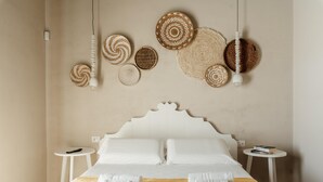 A neatly made bed with white linens and a beige blanket, two bedside tables with books, and a wall decorated with woven circular wall hangings and pendant lights. - Villa La Siesta - Ragusa (Ragusa)